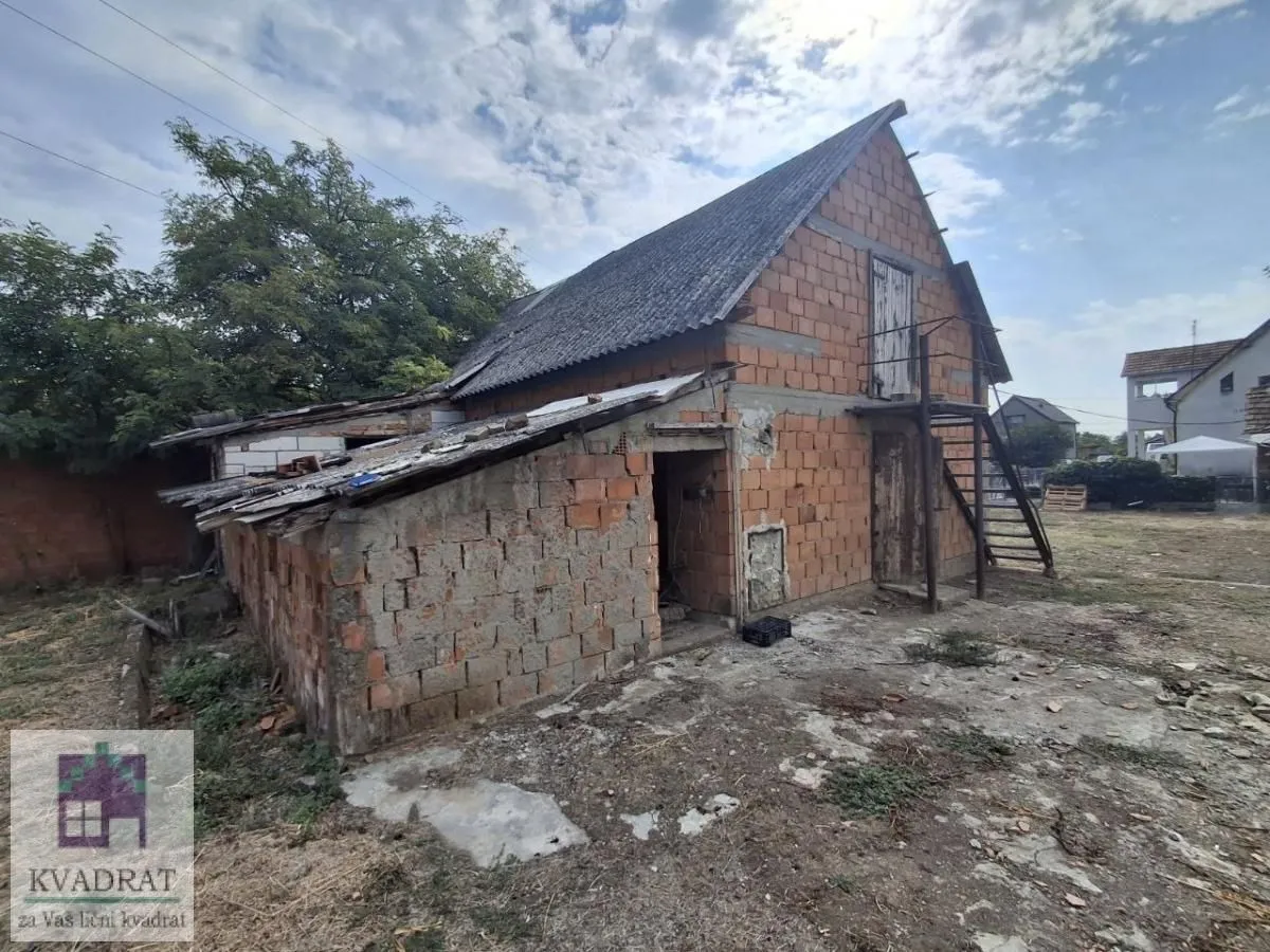 Pogled na spoljašnjost stare kuće od cigle sa pomoćnim objektom i dvorištem.