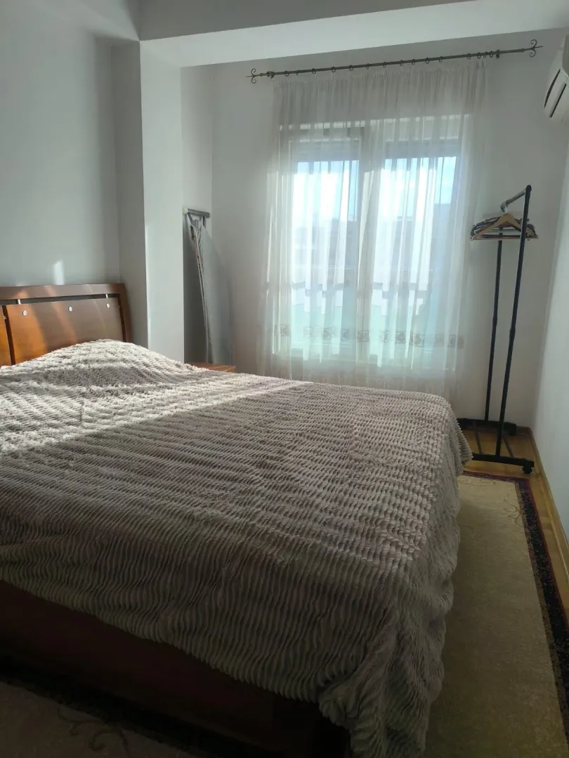Comfortable bedroom with a double bed and a window with white curtains.