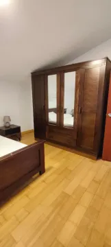 Furnished bedroom with a large wooden wardrobe and a bed. - image 8
