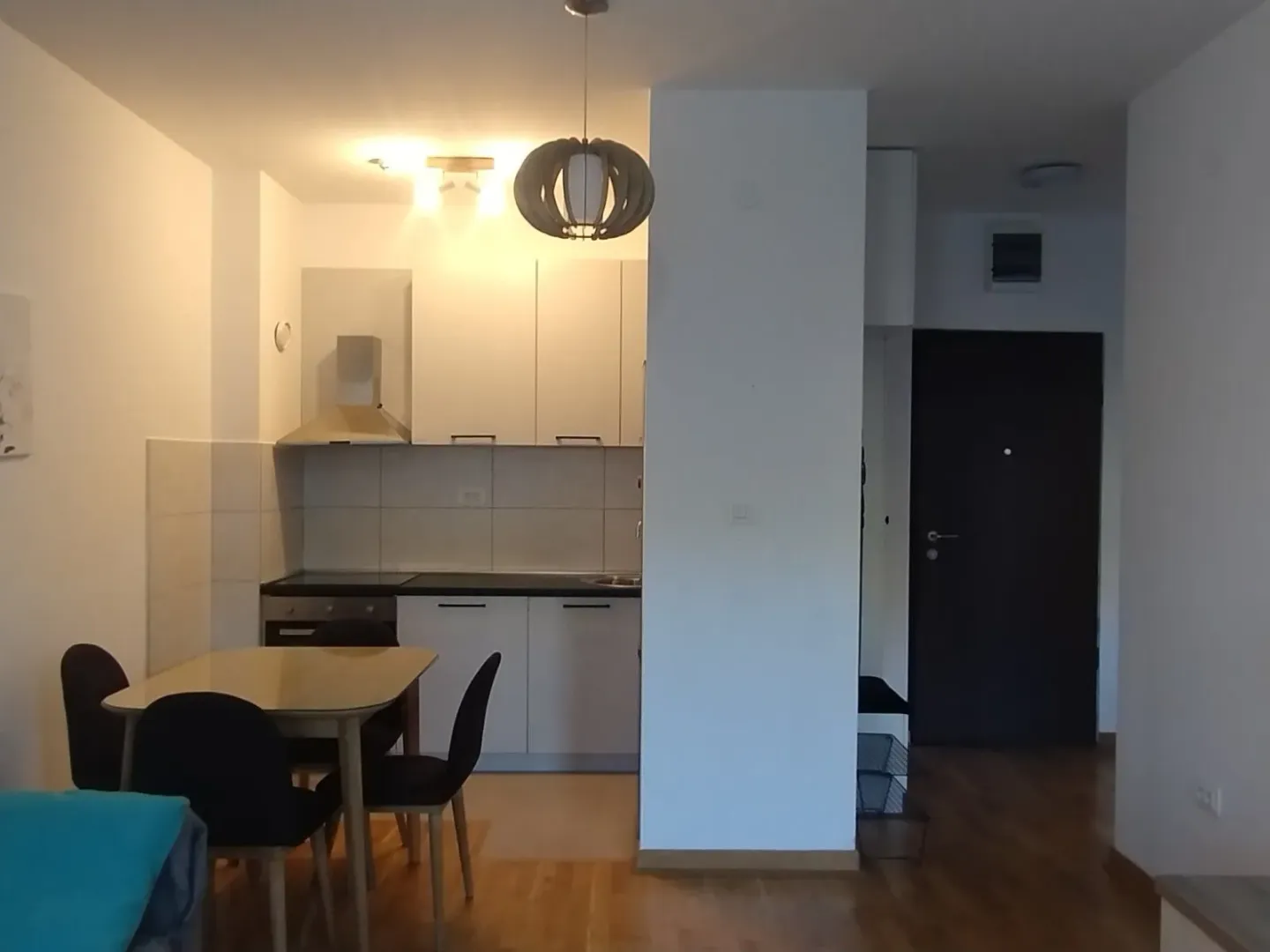 A kitchen with a dining table and a view of the entrance hallway.