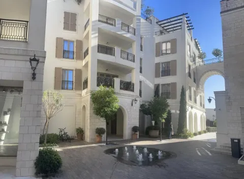 Modern residential complex with a paved courtyard, fountain, and landscaped greenery. - image 16