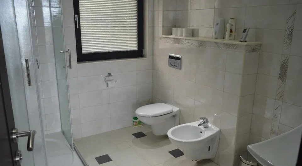 Moderne kupatilo sa tuš kabinom, WC šoljom, bideom i prozorom.