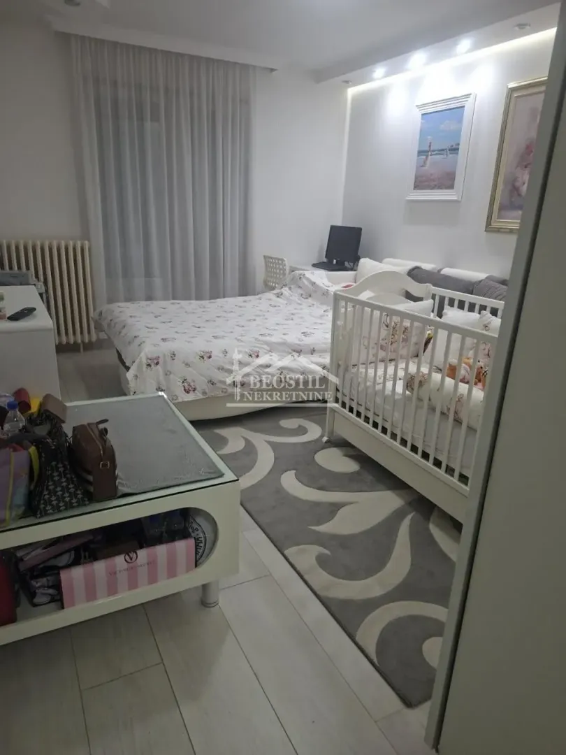 Furnished bedroom with a baby cot and a large double bed.