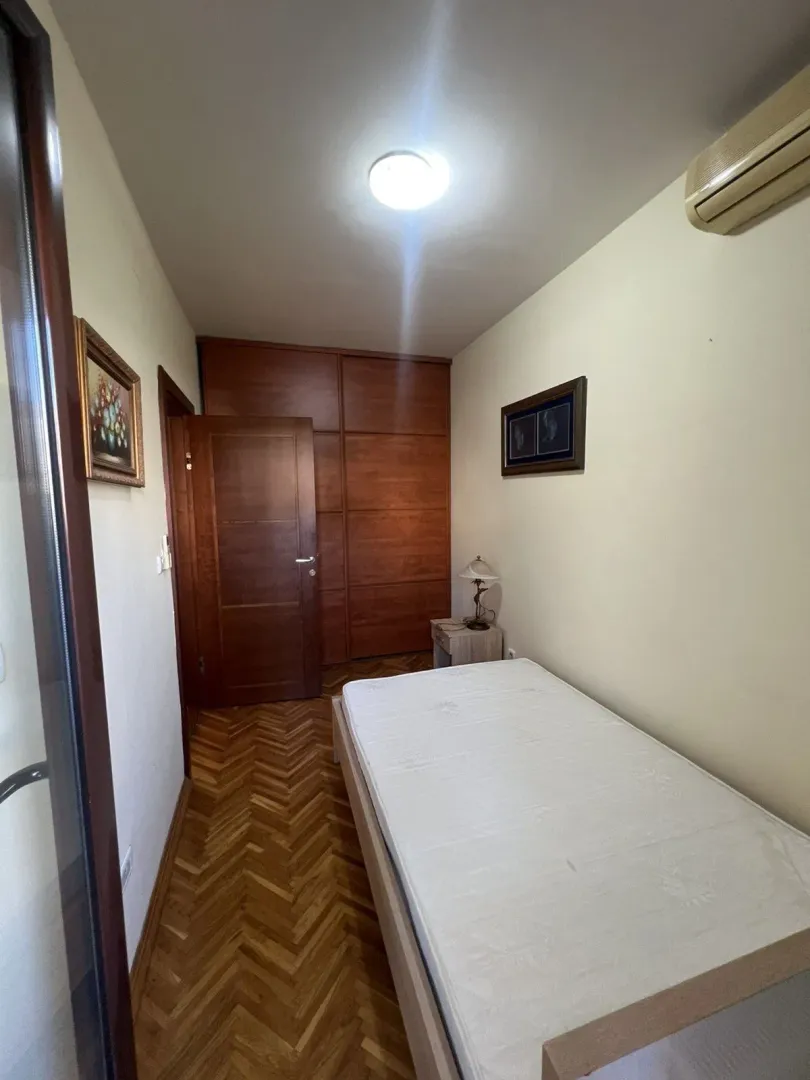 A small bedroom featuring a single bed and a wooden wardrobe.