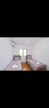 Bright bedroom with two single beds and an air conditioning unit. - image 5
