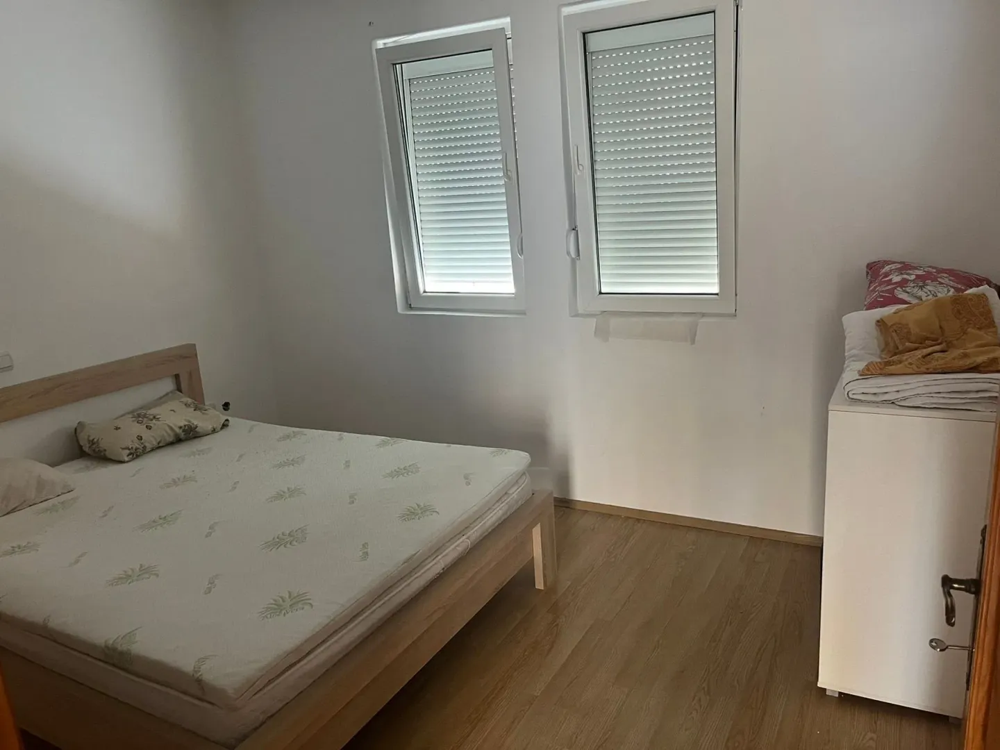 Manja spavaća soba sa krevetom i dva prozora.