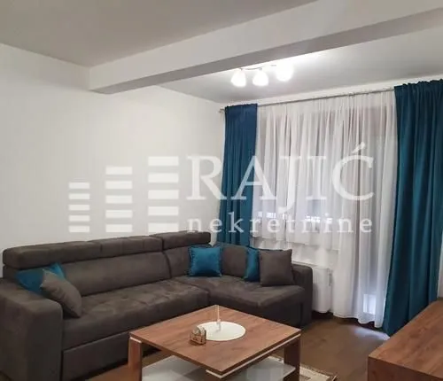 Living room with a sectional sofa and a window with blue curtains.