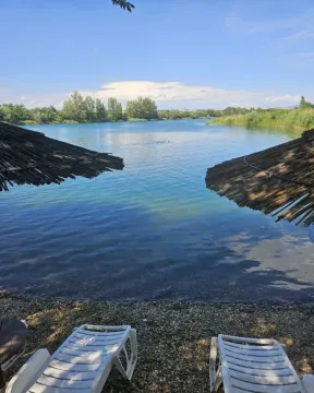 Pogled na jezero i obalu sa ležaljkama i suncobranima. - image 14