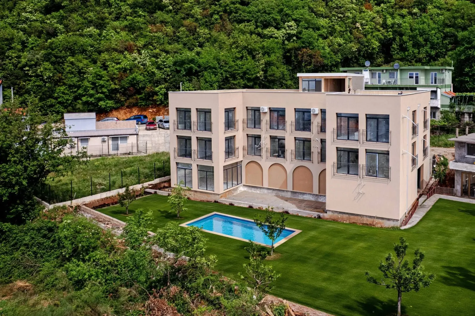 Aerial view of a modern residential building with a swimming pool and landscaped yard.
