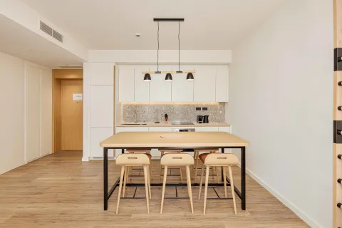 Moderna kuhinja sa bijelim elementima i trpezarijskim stolom sa barskim stolicama. - image 21