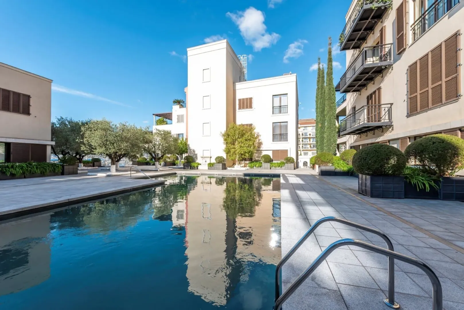 Vanjski pogled na zgradu sa bazenom i uređenim dvorištem.