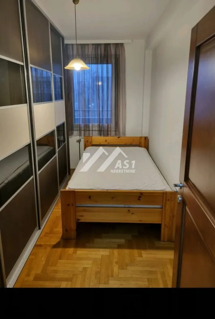 Smaller bedroom with a wooden bed and a large built-in wardrobe.