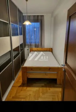 Smaller bedroom with a wooden bed and a large built-in wardrobe. - image 6