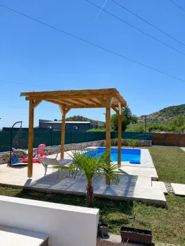 Yard with a swimming pool, wooden gazebo, and sun loungers. - image 4