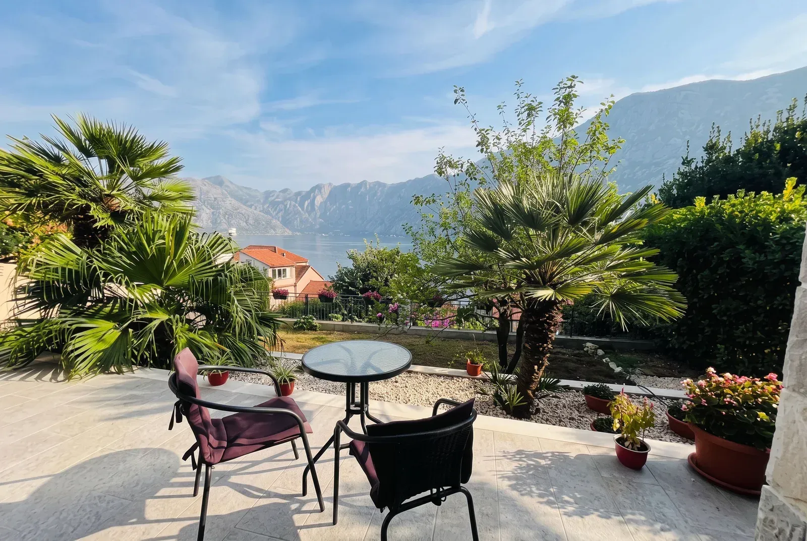 Namještena terasa sa garniturom za sedenje i pogledom na more i planine.