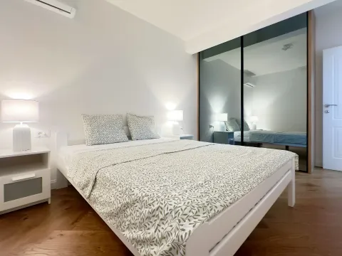 Bright bedroom with a double bed, bedside tables, and a large mirrored fitted wardrobe. - image 5