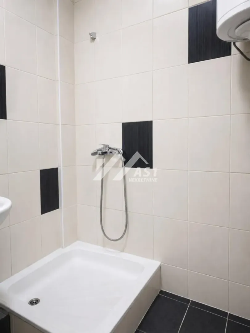 Pogled na tuš kabinu i keramičke pločice u kupatilu.