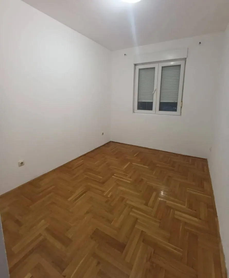 Prazna soba sa parketom i bijelim zidovima.
