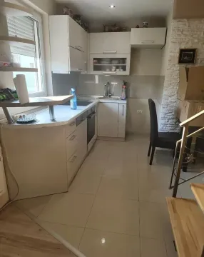 Manja opremljena kuhinja sa belim elementima i trpezarijskom stolicom. - image 2