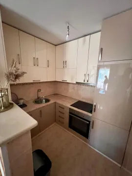 Small kitchen with light cabinetry, a sink, and a built-in oven. - image 7