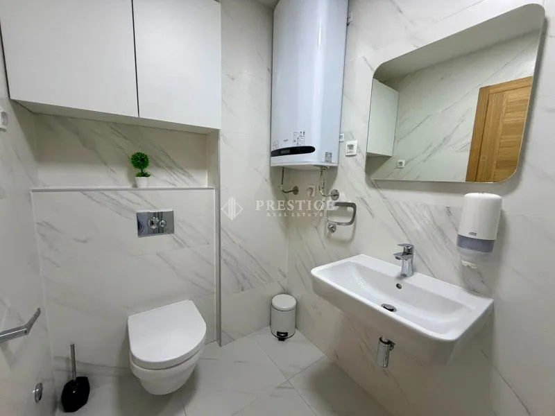 Moderno opremljeno kupatilo sa bijelim pločicama i ugradnim sanitarijama.