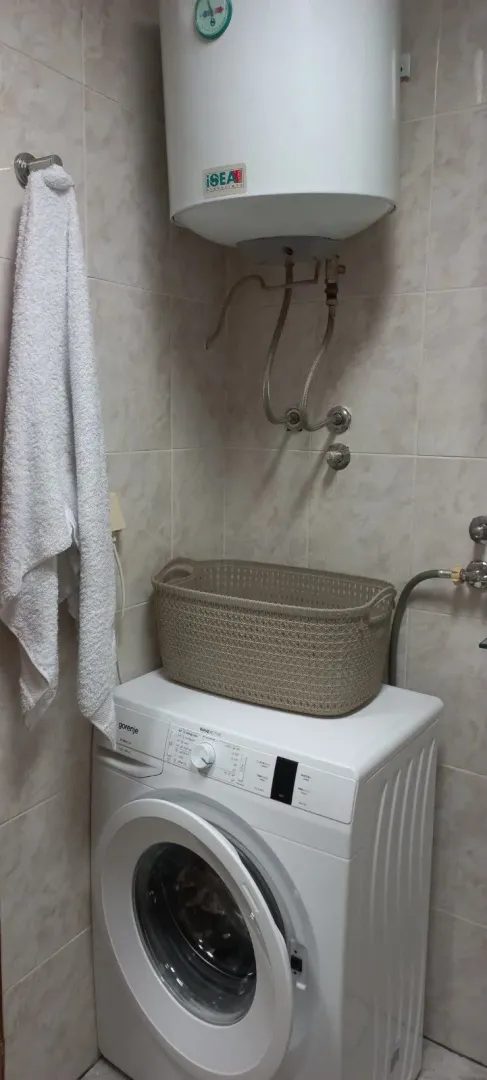 Smaller bathroom with a washing machine and water heater.