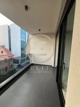 Unfurnished balcony with a glass railing and a view of surrounding buildings and the street. - image 12