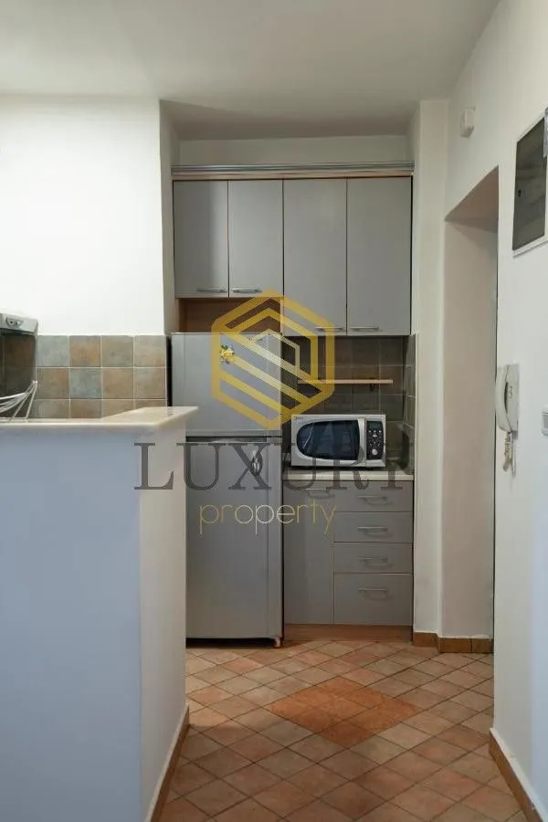 Smaller kitchen with grey cabinets and tiled floor.