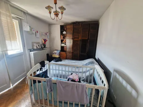 Spavaća soba sa krevetom, krevetcem i drvenim ormarom. - image 12