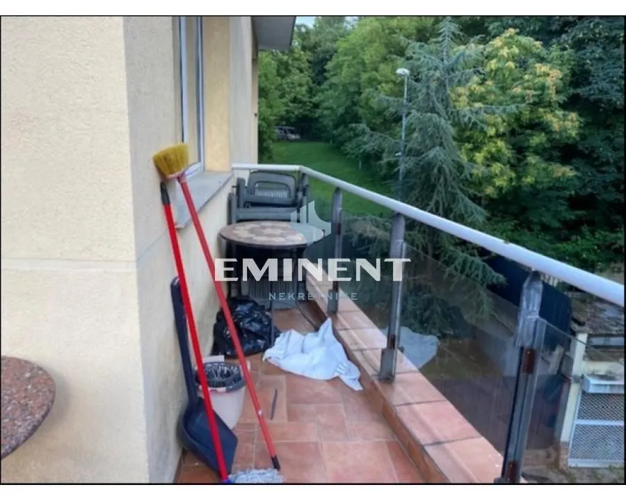 Small tiled balcony with a glass railing and a view of greenery.
