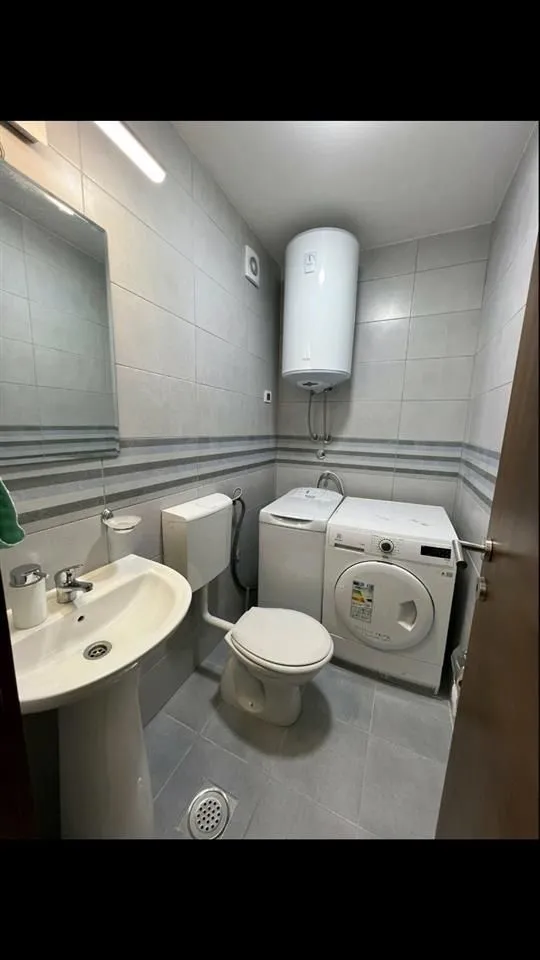 Jednostavno kupatilo sa lavaboom, toaletom i veš mašinom.