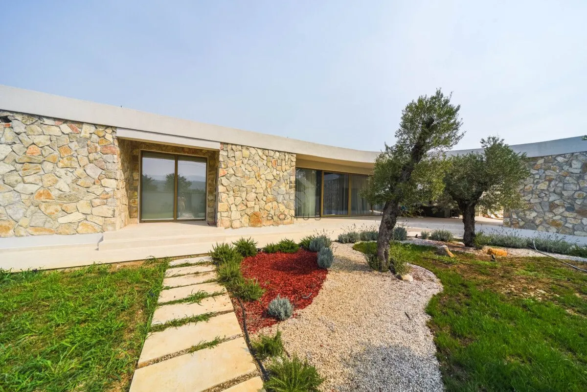 Exterior of a modern house with a stone facade and landscaped yard.