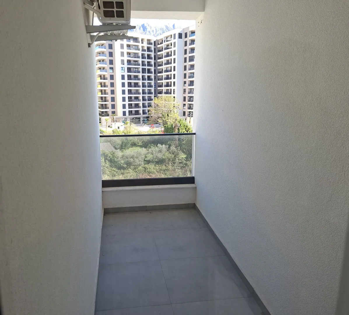 Empty balcony with a view of neighboring buildings and greenery.