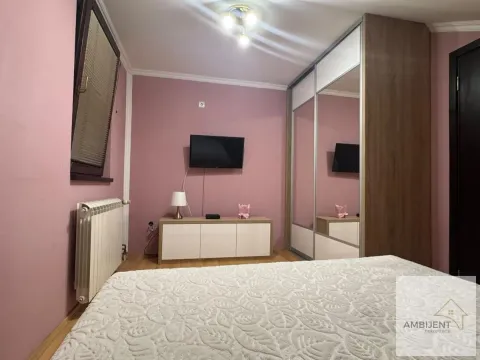 Nameštena spavaća soba sa krevetom, plakarom i televizorom na zidu. - image 12