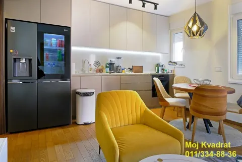 Moderna kuhinja sa trpezarijom i žutom foteljom u prvom planu. - image 4