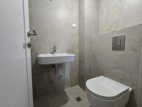Modern bathroom equipped with a washbasin and toilet bowl, tiled with ceramic tiles. - image 11