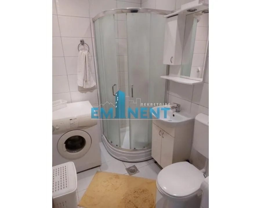 Bathroom equipped with a shower cabin, washbasin, toilet, and washing machine.