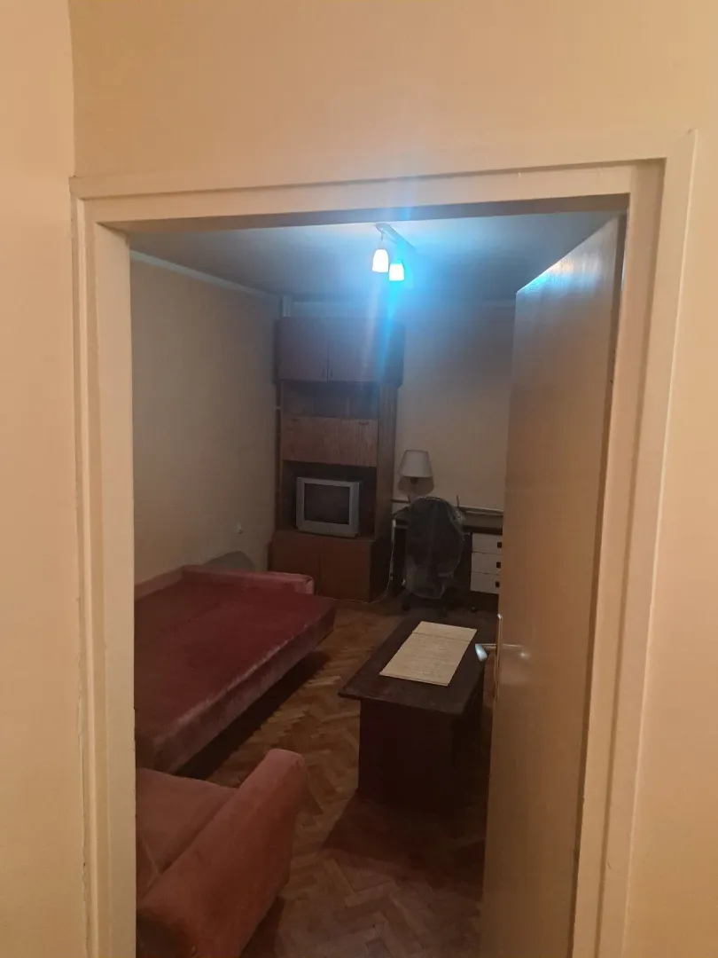 View through the doorway into a furnished living room with a sofa and wall unit.