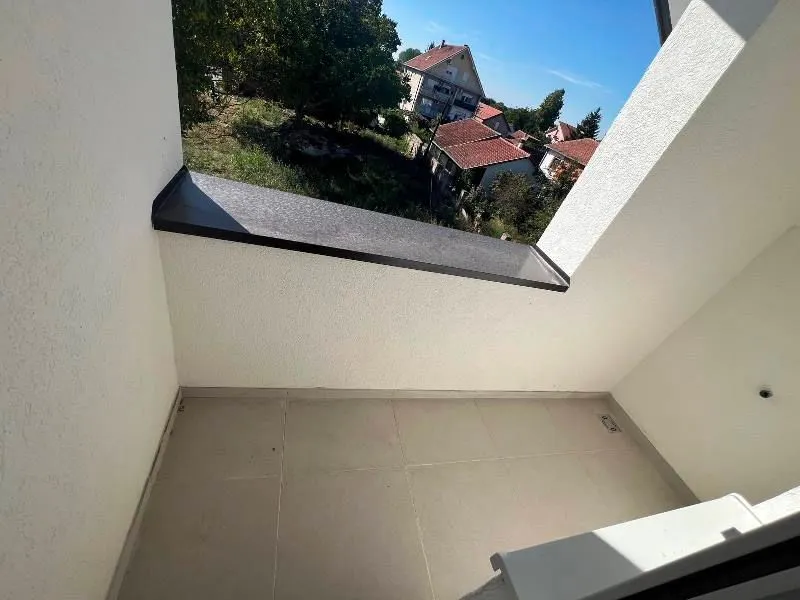 Pogled sa balkona na okolne kuće i zelenilo.
