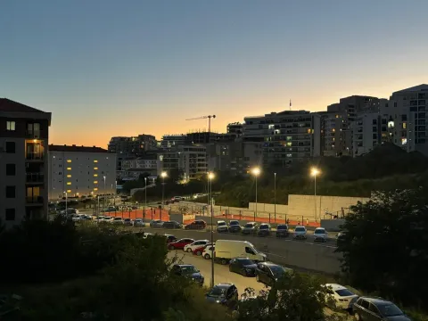 View of the city and illuminated sports field at dusk. - image 9