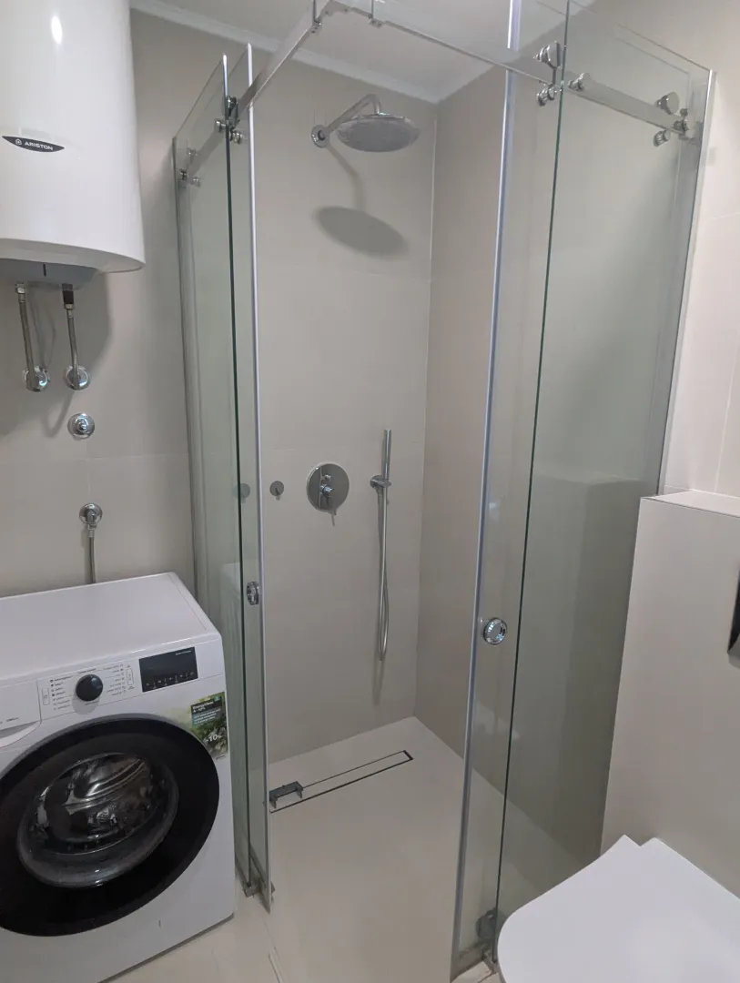 Modernly equipped bathroom with a shower cabin and washing machine.