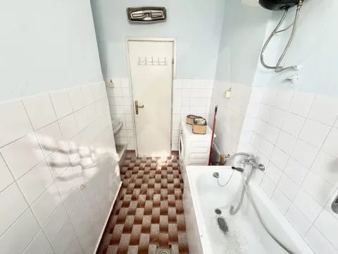Smaller bathroom with a bathtub, washing machine, and tiled walls and floor. - image 5
