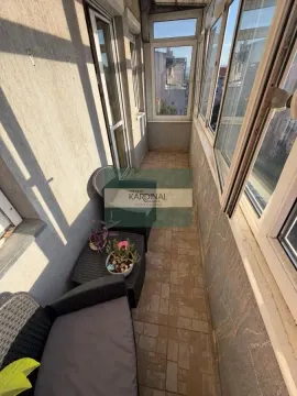 Zastakljeni balkon sa garniturom za sedenje i keramičkim pločicama na podu. - image 3