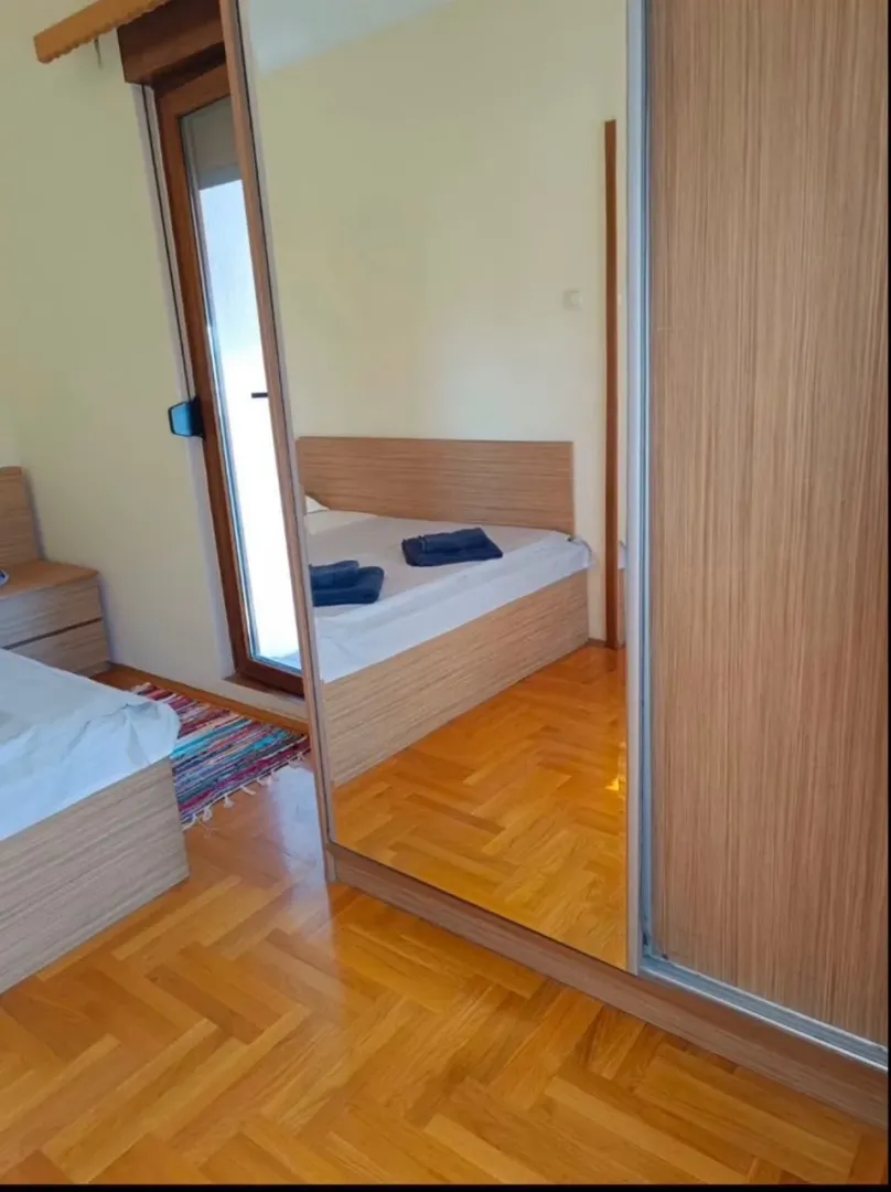 Spavaća soba sa drvenim krevetom i ormarom sa ogledalom.