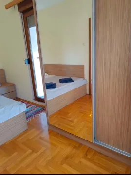 Spavaća soba sa drvenim krevetom i ormarom sa ogledalom. - image 3