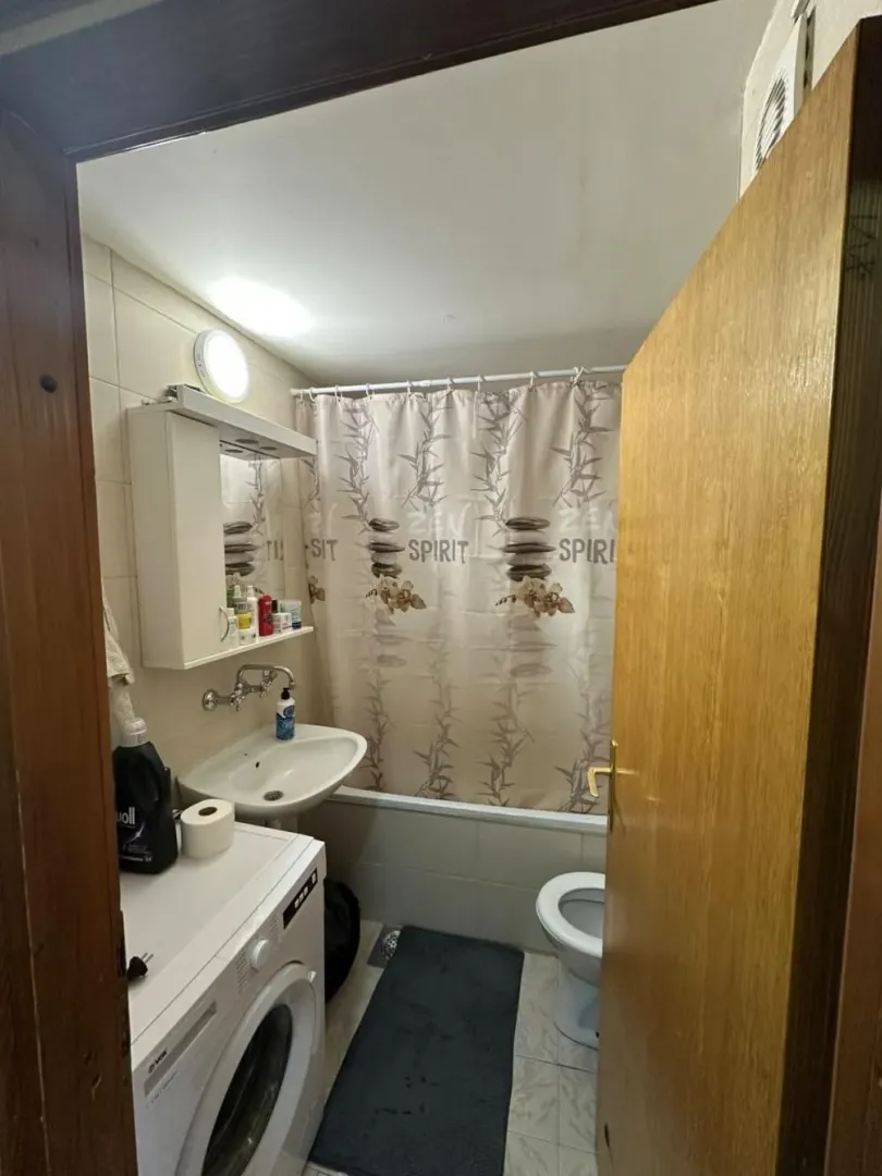 View of the bathroom with a bathtub, washbasin, and washing machine.
