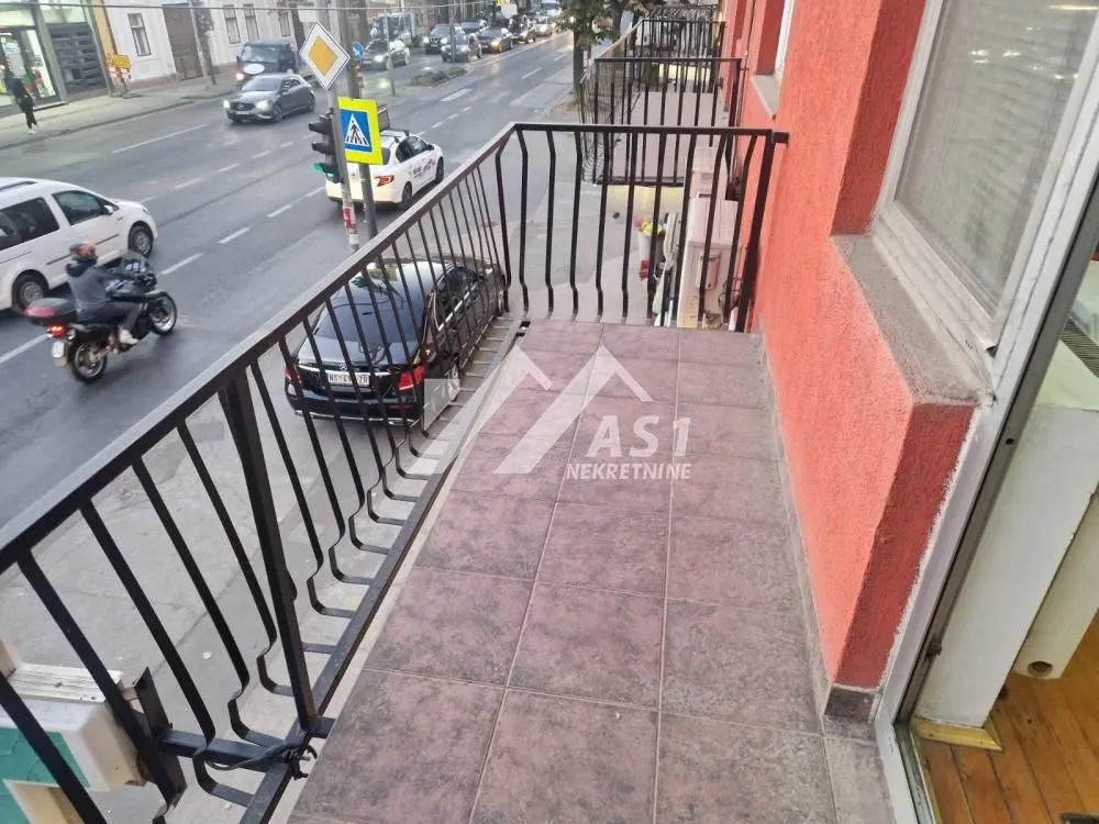Balkon sa metalnom ogradom i pogledom na ulicu.