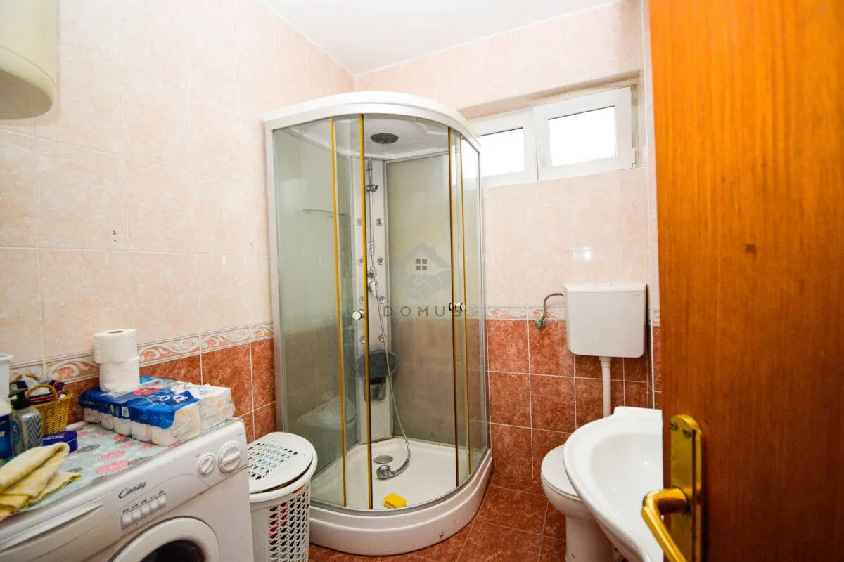 Bathroom equipped with a shower cabin, washbasin, toilet, and washing machine.