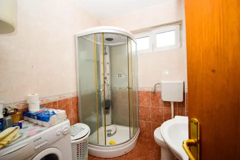 Bathroom equipped with a shower cabin, washbasin, toilet, and washing machine. - image 16