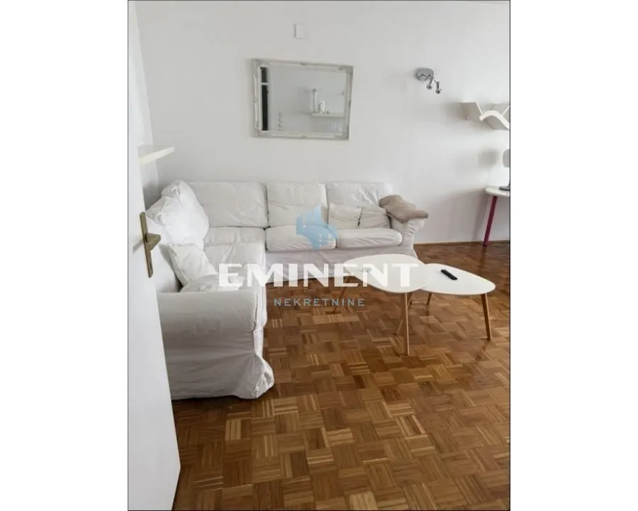 Living room with a white corner sofa and parquet flooring.